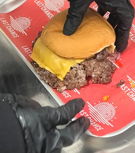 Ein fertiger Cheeseburger wird in die Box gelegt
